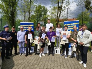 Grupa uczniów wraz z organizatorami turnieju stoją do zdjęcia grupowego z nagrodami i pucharami w rękach