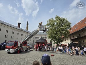Straż pożarna z wyciągniętą drabiną stoi na placu - grupa ludzi.