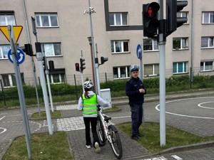 Uczeń na miasteczku ruchu drogowego podczas praktycznego egzaminu na kartę rowerową pod okiem policjanta ruchu drogowego.