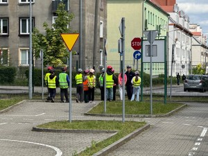 Stojący uczniowie na miasteczku ruchu drogowego podczas instruktażu policjanta