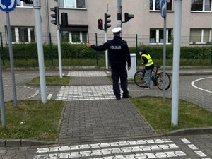 Uczeń na rowerze podczas egzaminu na kartę rowerowa i stojący obok umundurowany policjant drogówki