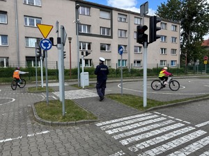 Egzamin na kartę rowerową. Policjant i uczeń na rowerze na miasteczku ruchu drogowego.