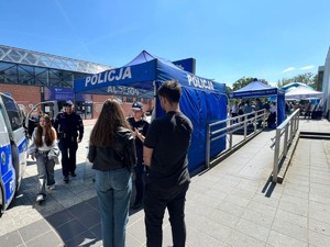 Stoisko profilaktyczne Policji Gliwickiej pod namiotem. Na pierwszym planie młoda para ludzi.