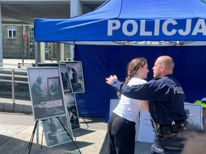 Umundurowany policjant prezentuje młodej kobiecie techniki samoobrony