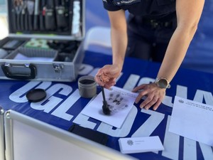Pobieranie linii papilarnych na stoliku leży arkusz papieru, po którym przesuwany jest pędzel