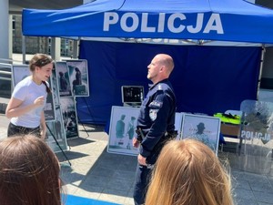 Pokaz samoobrony. Na macie umundurowany policjant a młodym człowiekiem