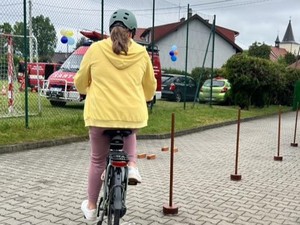 Dziewczynka jedzie rowerem po rowerowym torze przeszkód