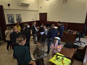 grupa osób znajduje się na sali sądowej. Oglądają wyposażenie Policji