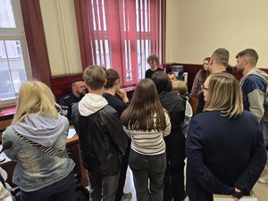 Grupa zwiedzających stoi na sali sądowej