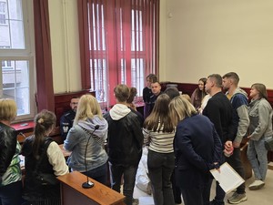 Grupa zwiedzających stoi na sali sądowej