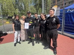 Grupa uczniów klasy mundurowej stoi na boisku szkolnym