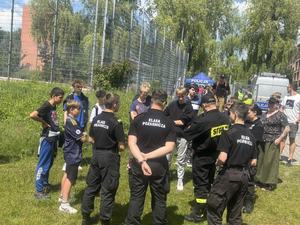 Grupa uczniów stoi tyłem na boisku szkolnym