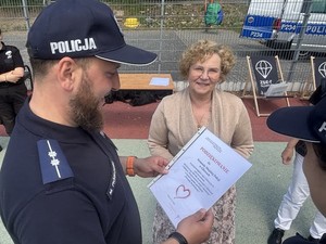 Umudurowany policjant z dyplomem w ręku stpi z Dyrektor Ośrodka