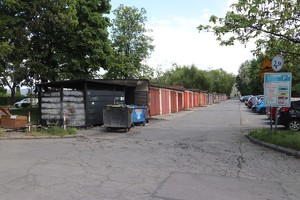 Na zdjęciu spalona wiata śmietnikowa ,przy garażach i zaparkowane pojazdy