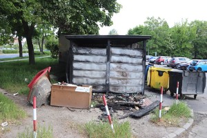 Na zdjęciu spalona wiata śmietnikowa i nadpalone kontenery na śmieci.