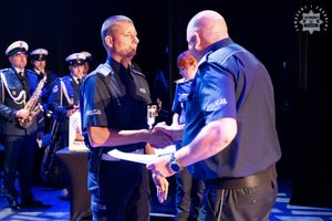 Na zdjęciu policjant odbierający nagrodę na scenie w konkursie od Komendanta Policji.