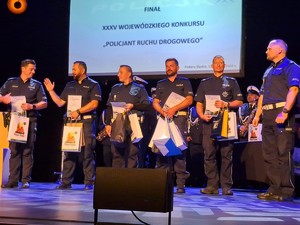 Zdjęcie nagrodzonych policjantów stojących na scenie.