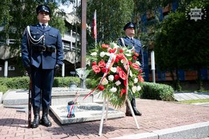 Policjanci ubrani na galowo stoją przed grobem na terenie Komendy Wojewódzkiej Policji w Katowicach.