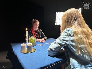 Kobiety siedzące przy biurku - jedna to wróżka, a druga to studentka pytająca o wakacje.