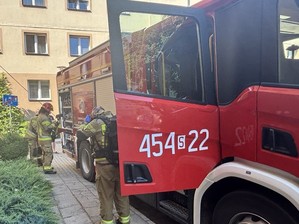 Przy wozie bojowym Straży pożarnej czynności wykonują strażacy.
