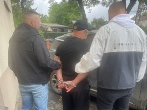 Na zdjęciu widocznych dwóch nieumundurowanych policjantów prowadzących zatrzymanego.