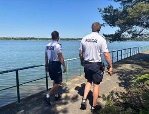 Dwóch policjantów idzie nabrzeżem jeziora
