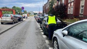 Na zdjęciu widzimy uszkodzone pojazdy i policjanta z dokumentacja