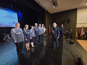Umundurowani policjanci stojący na scenie.