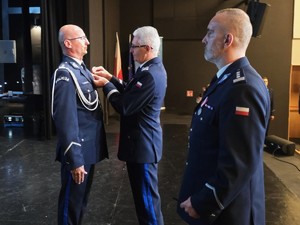 Na scenie generał wręcza policjantowi odznaczenie. Obok stoi Komendant KMP w Gliwicach