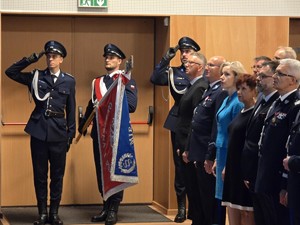 Poczet sztandarowy. Trzech umundurowanych policjantów stoi pod ścianą