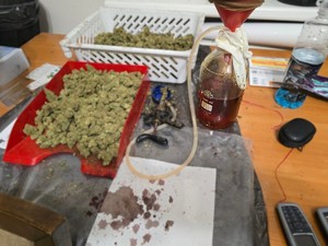 Na stole w plastikowych kuwetach znajduje się susz roślinny oraz sprzęt wykorzystywany przez przestępców