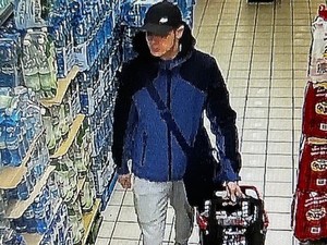 Mężczyzna w czapce bejsbolówce i kurtce czarno-granatowej w sklepie przy półce