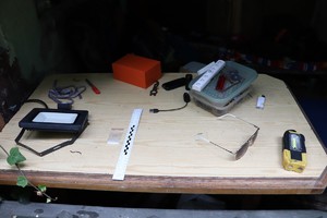 Na stole leży lampa okulary, telefon i biały woreczek z zawartością środków odurzających.