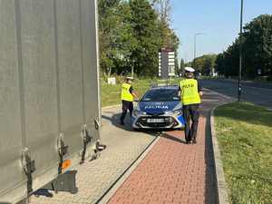Policjanci po zakończonej kontroli drogowej podchodzą do radiowozu.
