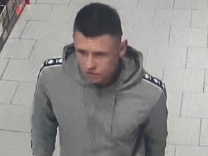Młody mężczyzna w jasnej szarej bluzie i krótkich ciemnych włosach