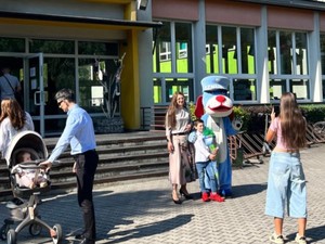 Sznupek przed wejściem do szkóły z dziećmi i dorosłymi.