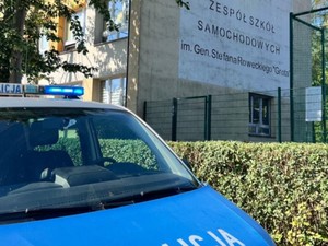 Zdjęcie radiowozu na tle szkoły.