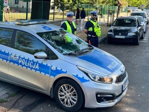 Radiowóz oznakowany Policji i umundurowani policjanci pełnią służbę w rejonie szkoły.