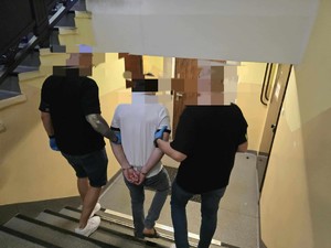 Dwóch policjantów nieumundurowanych sprowadza zatrzymanego po schodach