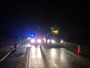 Na jezdni stoją dwa pojazdy po zdarzeniu drogowym oraz radiowóz policyjny na włączonych światłach błyskowych.