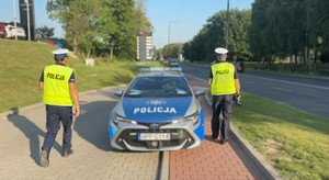 Policjanci drogówki podchodzą do radiowozu