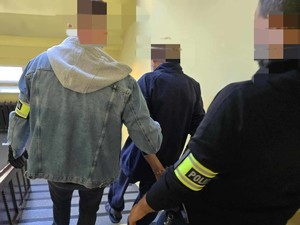 Dwóch nieumundurowanych policjantów sprowadza zatrzymanego po schodach