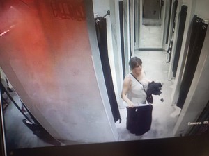 Na zdjęciu młoda kobieta w ciemnych włosach wychodząca z przebieralni w sklepie.