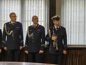 Pod oknem stoi I Zastępca oraz Zastępca Komendanta Miejskiego Policji w Gliwicach. Tuż obok nich trębacz.