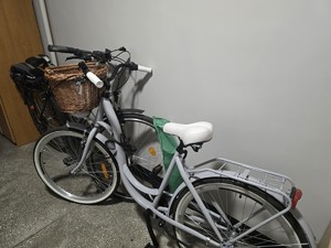 Rowery stojące, przypięte do rurki na korytarzu.