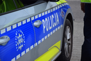 bok radiowozu policyjnego i stojący obok policjant.