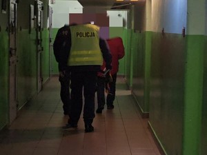 Policjanci prowadzą zatrzymanego w pomieszczeniu dla osób zatrzymanych.