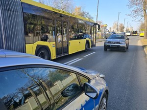 Na jezdni w rejonie cmentarza widzimy autobus komunikacji miejskiej, Policji i Straży Miejskiej.