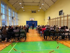 Z mikrofonem przed rodzicami uczniów szkoły w Wilcze przemawia asp. Mateusz Piórkowski.