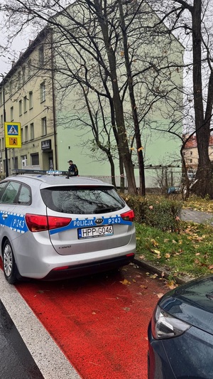 Widok na budynek, a przed nim stojące radiowozy.